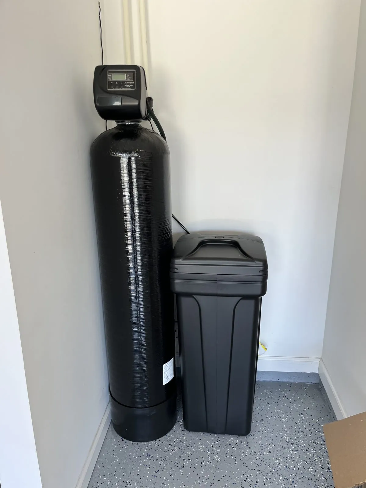 Softener resin tank and brine tank in the corner of a finished garage
